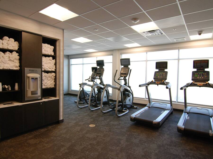 Un gimnasio con cintas de correr, elípticas y una fuente de agua.