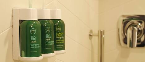 A bathroom with three bottles of shampoo and body wash on a dispenser.