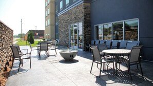 An outdoor patio area with stone walls, a stone fireplace, and multiple tables and chairs.