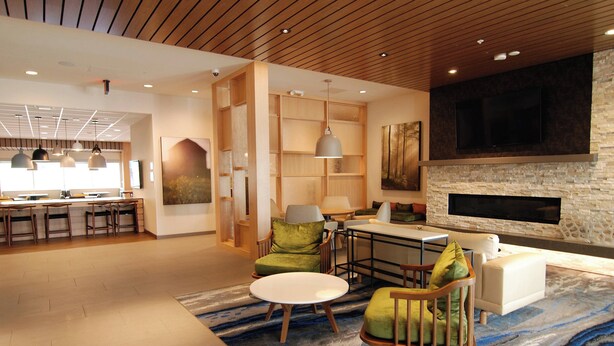 A modern hotel lobby with a dining area, seating arrangements, and a stone fireplace.