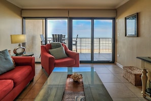 Relax in this stylish room with a sofa, armchair, and glass coffee table, offering a view of the beach.