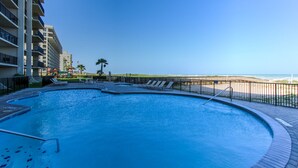 Une piscine avec des chaises longues et vue sur la plage.