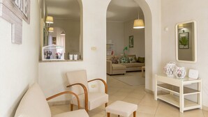 A living room with a sofa, chairs, a coffee table, and a mirror. - Casa Amica Giardini Naxos (Giardini Naxos)