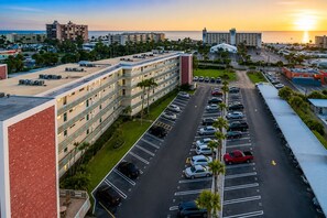 A multi-story hotel with a parking lot, a view of the ocean, and a clear sky.
