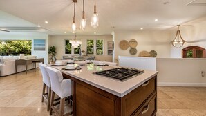 A spacious kitchen with a central island, pendant lighting, and a view of the outdoors. - Summer Deal Ocean View Wailea Villa with Pool and Resort Hot Tubs (Wailea)