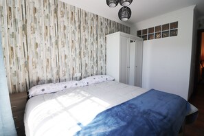 A bedroom with a bed, a wardrobe, and a window with decorative glass panes. - 1093 Villa Magnolias (Torrox)