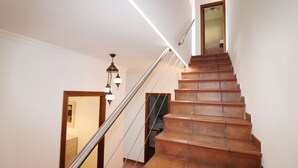 Un escalier avec des marches en bois et une rampe métallique, menant à l’étage supérieur.