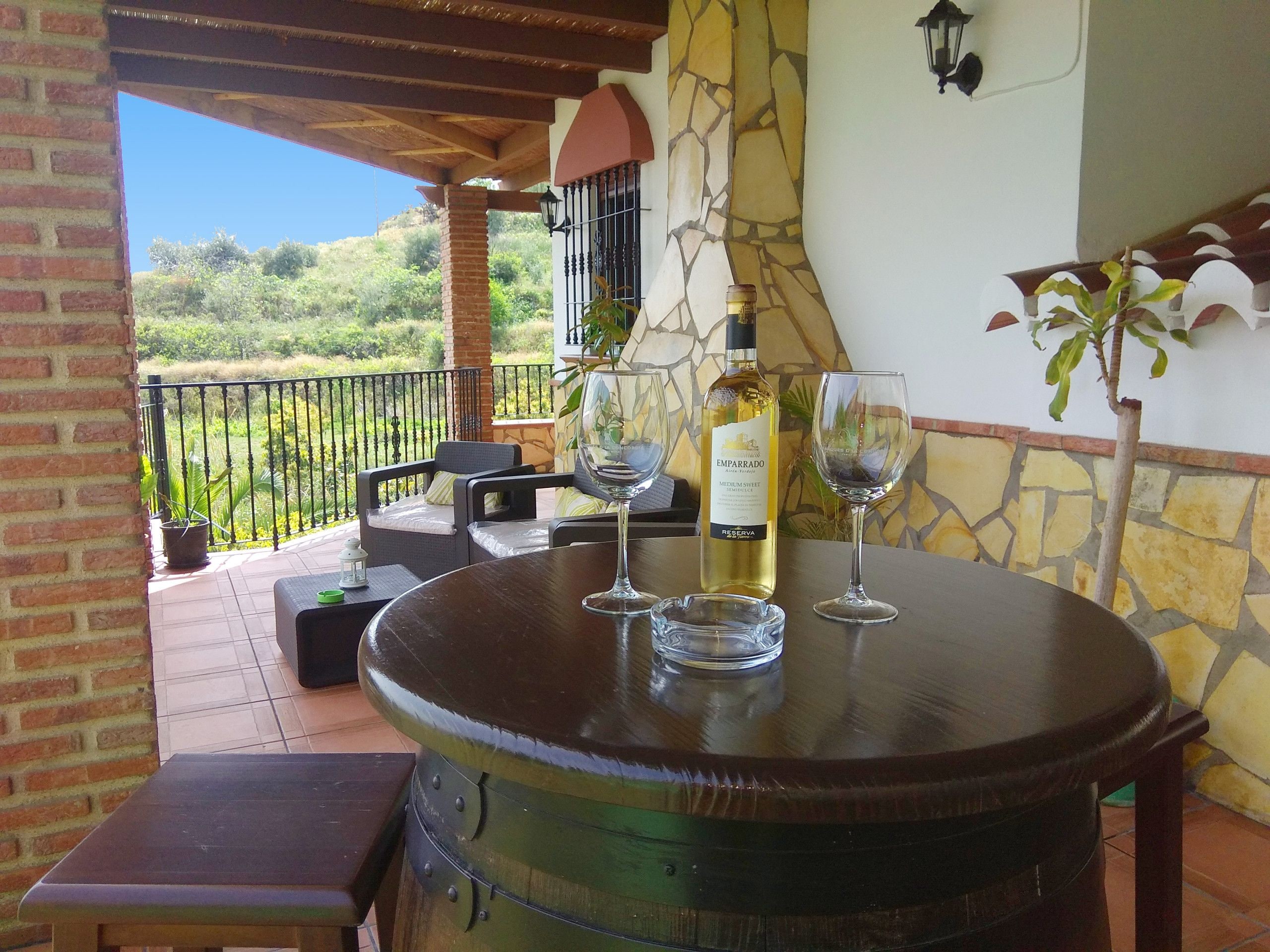 A patio with a round table, two chairs, a wine bottle, and two wine glasses.