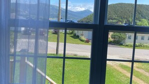 A window with a view of a parking lot, grassy area, and a mountain in the distance.