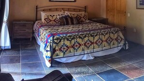 Une chambre à coucher avec un lit, une table de chevet, une porte en bois et un tableau encadré au mur.
