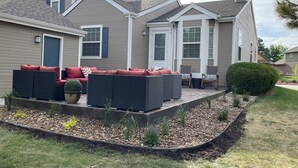 A residential exterior with a patio area featuring outdoor furniture and a well-maintained garden.