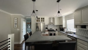 A modern kitchen with a central island, stainless steel appliances, and pendant lighting.