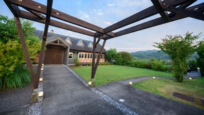 Una estructura de pérgola de madera con vista a una casa y follaje circundante.