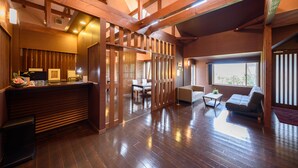 Amplia habitación con vigas de madera, mostrador de recepción, zona de comedor y área de estar con sofá y mesa de centro.