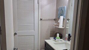Un bagno con il water, un lavandino con articoli da toilette, un portascopevoli e uno specchio illuminato.
