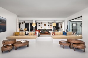 A modern living room with two sofas, wooden coffee tables, and a dining area with chairs and a table.