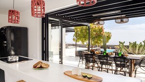 Una cocina moderna con encimera blanca, refrigerador negro y comedor con sillas y una mesa lista para una comida.