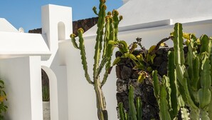 Un edificio blanco con pared de piedra y cactus al frente.