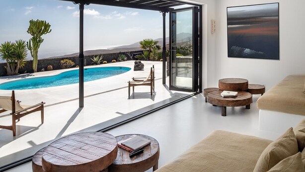Un interior moderno con piscina, mobiliario exterior y vistas al océano y montañas.