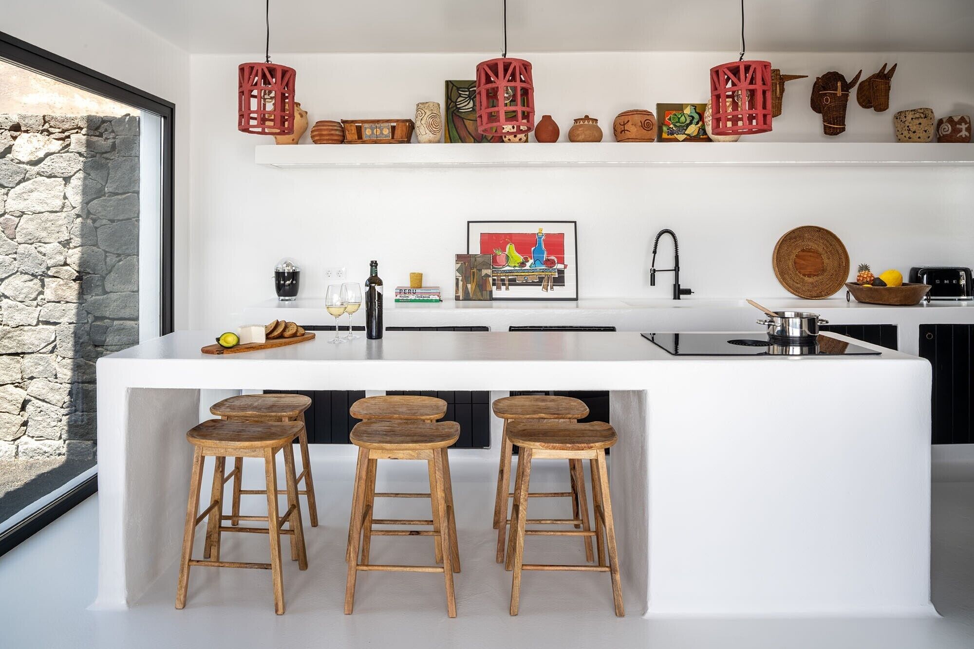 Une cuisine moderne dotée d’un îlot central, de tabourets en bois, de lanternes rouges suspendues et de divers ustensiles de cuisine.