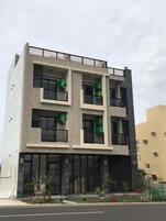 Un edificio moderno de varios pisos con techo plano, ventanas grandes y balcones.