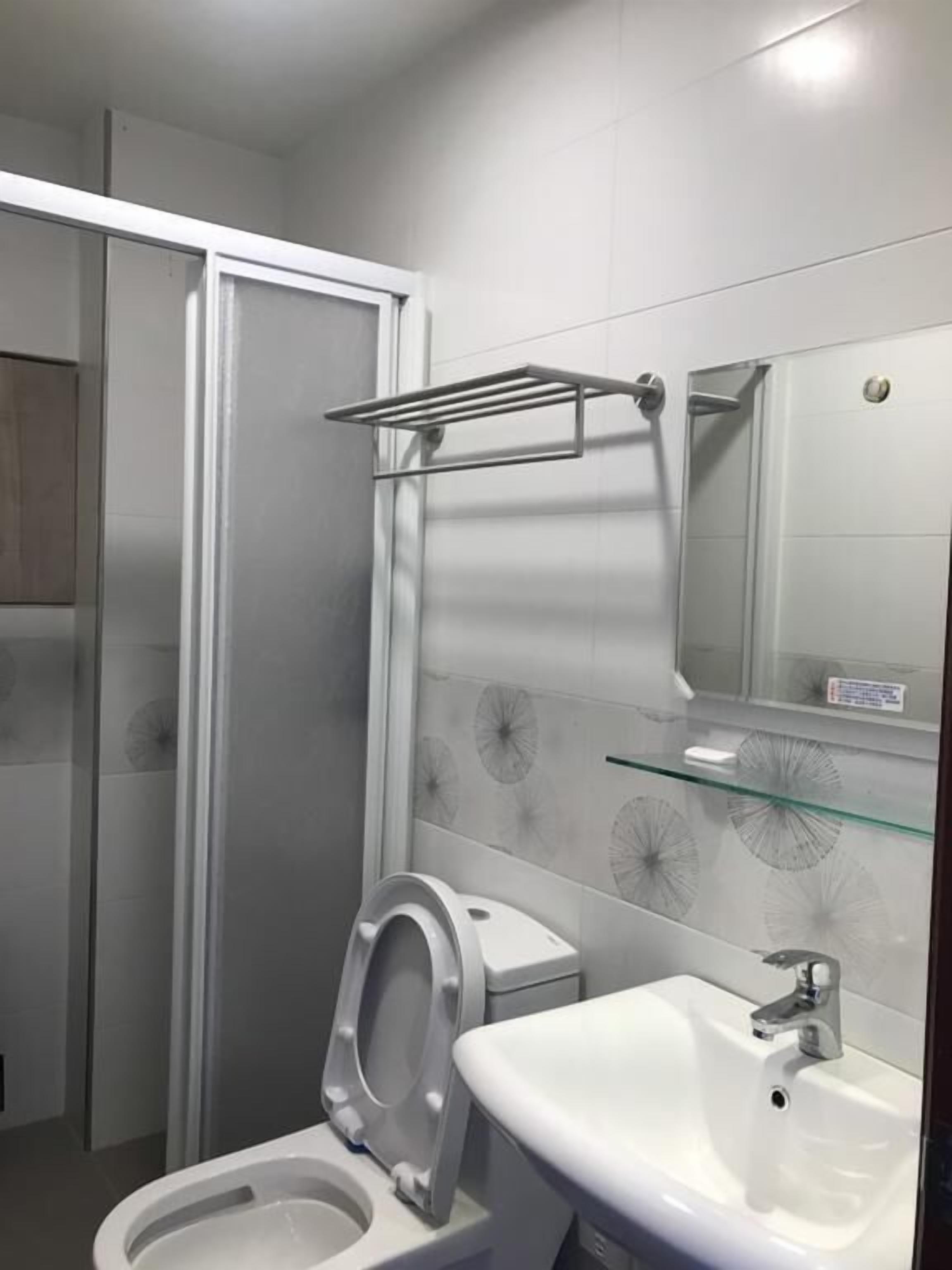 Un baño moderno con inodoro, lavamanos y cabina de ducha de vidrio.