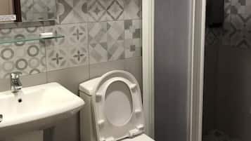 A bathroom with a toilet, sink, and shower area.