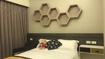 A hotel room with a bed, a headboard, a wall-mounted hexagonal shelf, a bedside table, and a curtain.