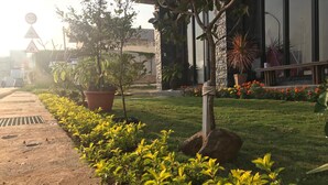 A landscaped garden with a pathway, potted plants, and a building with a stone facade.