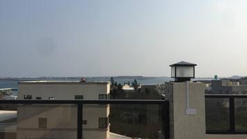 A high-rise building with a view of a body of water and distant hills.