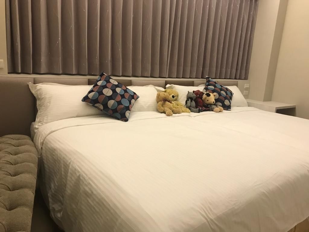 A neatly made bed with white bedding, a tufted headboard, and decorative pillows.
