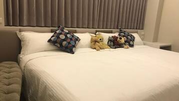 A neatly made bed with white bedding, a tufted headboard, and decorative pillows.