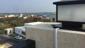 A modern building with a rooftop terrace overlooking a coastal area.