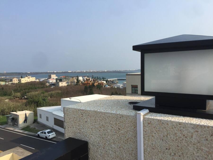 A modern building with a rooftop terrace overlooking a coastal area.