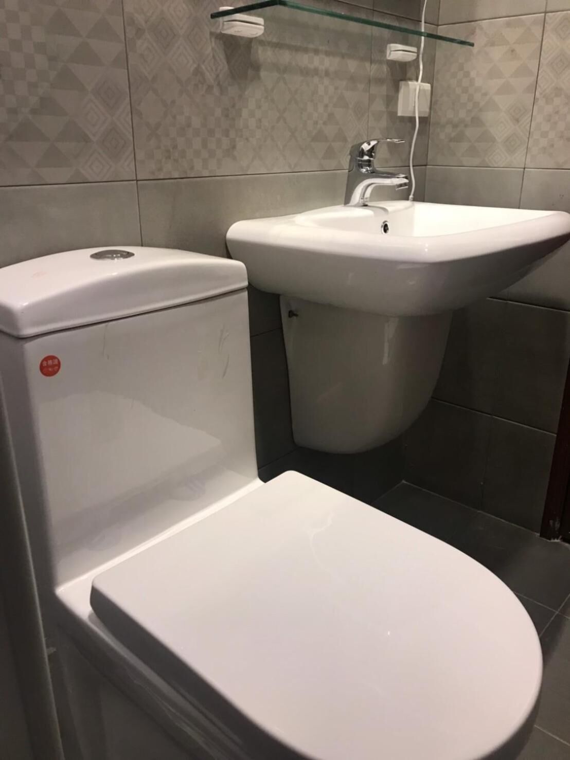 Et badeværelse med toilet, vask og glashylde.