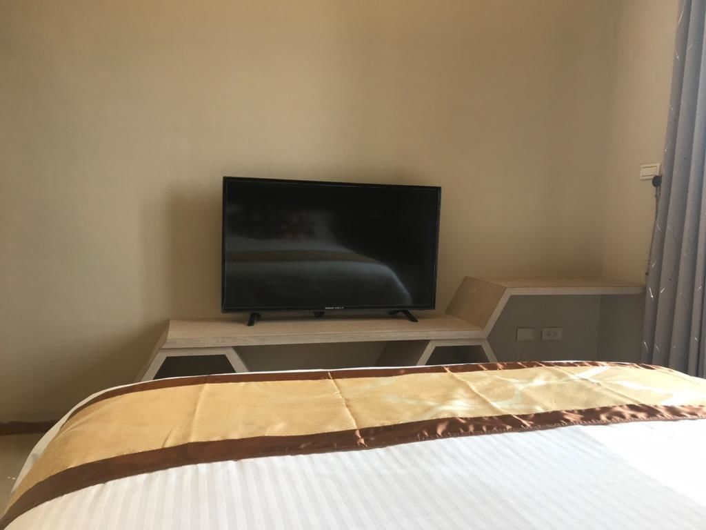 Una habitación de hotel con una cama, un televisor sobre un mueble y una puerta.