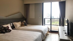 A hotel room with two beds, a TV, and a balcony with a view.