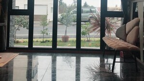A spacious room with a large window, a plush sofa, and a reflective floor.