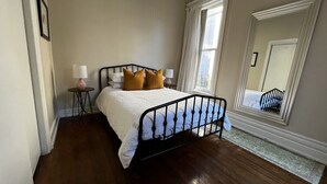 Ein Schlafzimmer mit einem Bett, zwei Nachttischen, einem Spiegel und einem Fenster.
