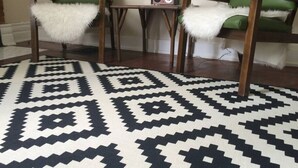 Ein Zimmer mit zwei grünen Stühlen, einem kleinen Tisch und einem Teppich mit Muster.