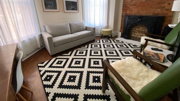 Ein Wohnzimmer mit einer Couch, einem Teppich mit Muster, einem Kamin und einem kleinen Tisch.