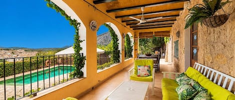 Un espacio al aire libre techado con piscina, asientos y vistas al paisaje.