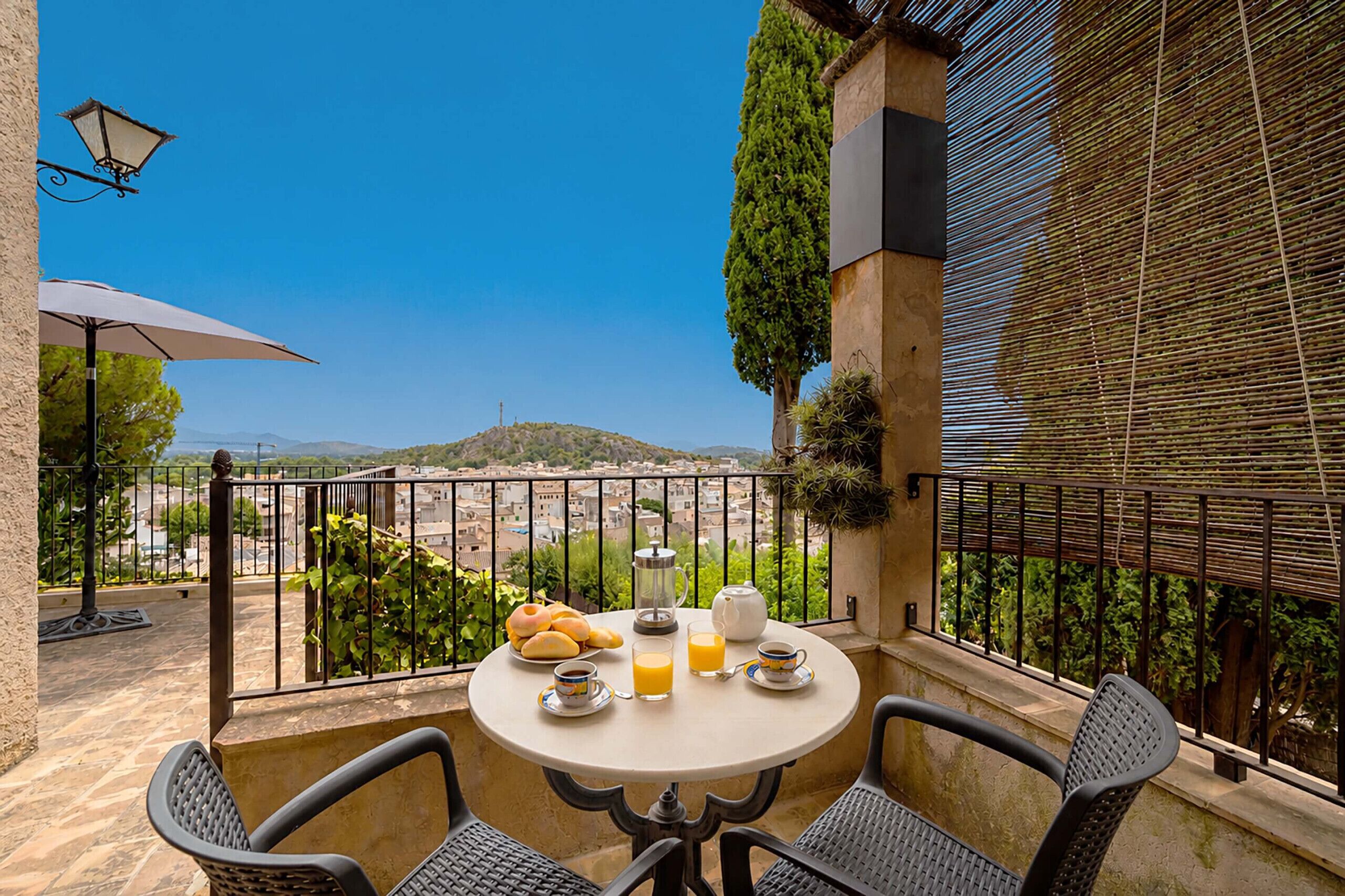 Une table ronde avec vue sur le paysage urbain, un panier de pain, une tasse de café, un verre de jus d’orange et une théière.