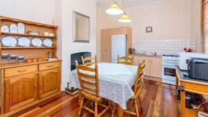 Una cocina acogedora con armarios de madera, una mesa de comedor con sillas, un refrigerador y una estufa.