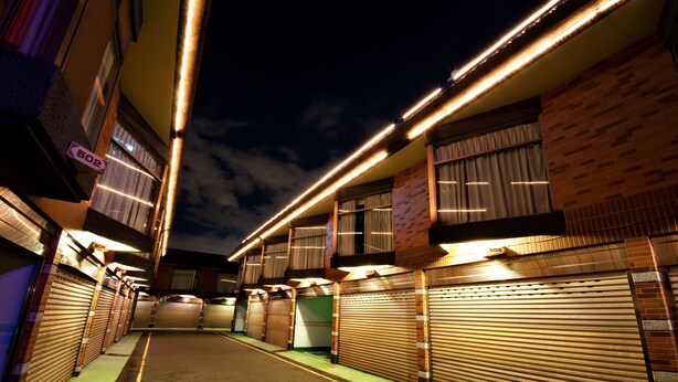 A row of closed hotel rooms with a green carpeted floor and a brick facade. - Beverly Commercial Motel (Taoyuan City)