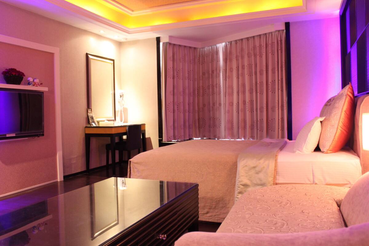 A hotel room with a bed, a desk, a chair, and a TV.