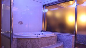 A bathroom with a marble tub, a glass shower enclosure, and a tiled floor. - Beverly Commercial Motel (Taoyuan City)