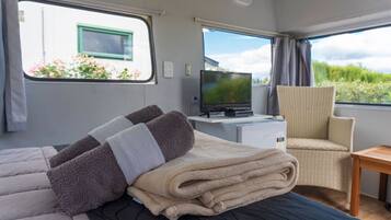 A cozy room with a bed, a television, and a chair.