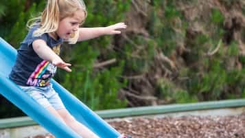 Un niño en un tobogán azul en un parque infantil.