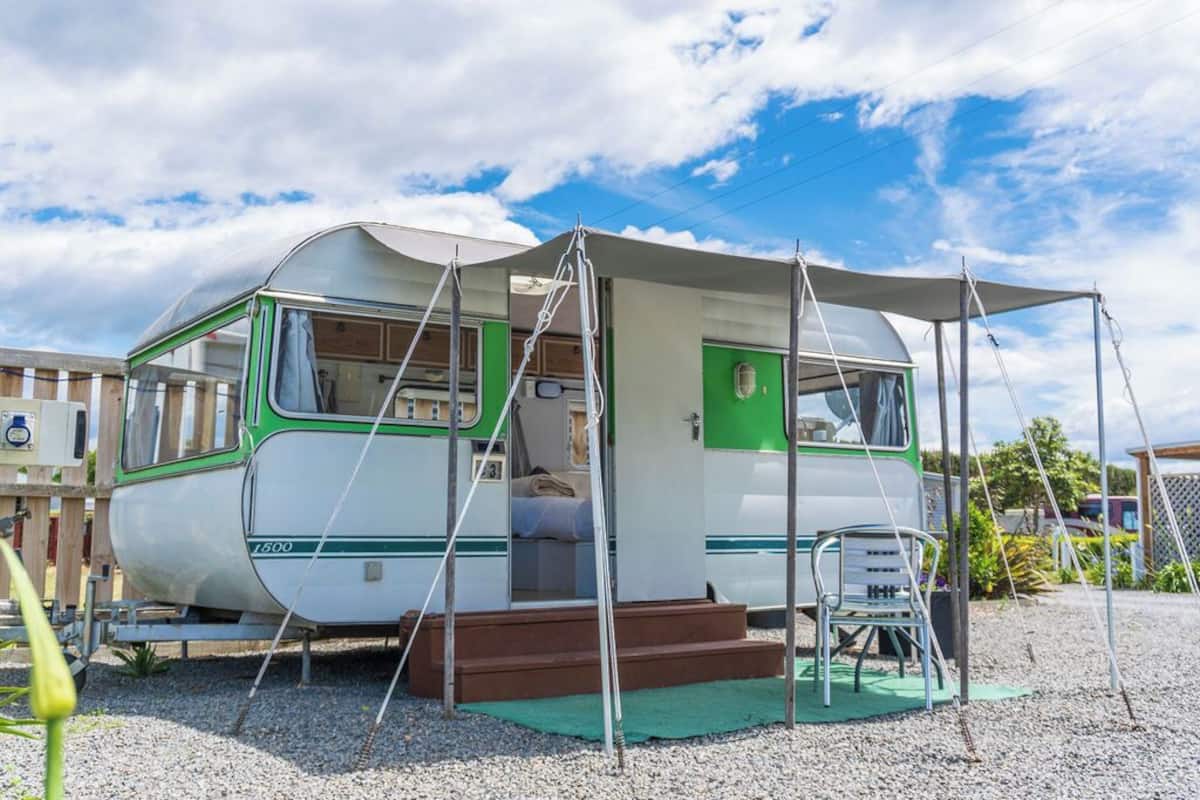 Uma casa de camper vintage com entrada coberta, um pequeno alpendre e um degrau para entrar.
